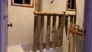 Un baño con cortina de bambú, una ventana pequeña y un espejo.
