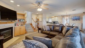A spacious living room with a large leather sofa, a flat-screen TV, and a fireplace. - 5BR Steps to Beach & Boardwalk! Beach tags & 3 parking spaces included! (Ocean City)