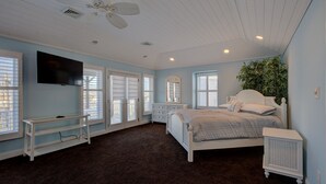 A bedroom with a bed, a TV, a ceiling fan, and a large window with blinds. - 5BR Steps to Beach & Boardwalk! Beach tags & 3 parking spaces included! (Ocean City)