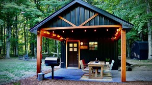 Un rustico chalet in legno con veranda coperta, tavolo da pranzo e posti a sedere all'aperto.