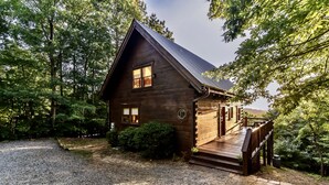 A wooden cabin with a porch, surrounded by trees. - Spacious Retreat~ Hot Tub~ Stunning Views~ Game Room (Mineral Bluff)