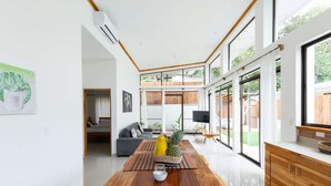 A modern interior with a dining area, a sofa, and a kitchen with wooden cabinets. - Villa Koi - Modern and Sophisticated Villa close to the Beach (Santa Teresa beach)