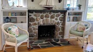 A cozy room with a stone fireplace, two wicker chairs, and a small table. - The beach is waiting. (East Lyme)