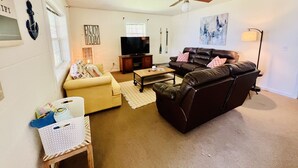 A living room with a sofa, a coffee table, a TV, and a ceiling fan.