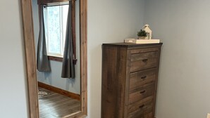 Quarto com um espelho grande, penteadeira de madeira e janela com cortinas.