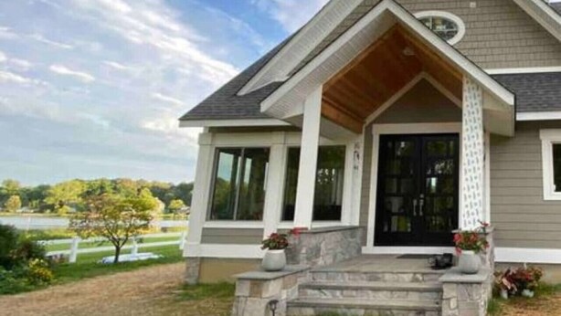 A modern two-story house with a gabled roof, large windows, and a front porch with steps. - Chesapeake Paradise House-Stunning 6+br4ba Wtrfrnt (Deale)