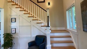 A staircase with white railings and wooden steps, a blue chair, and framed pictures on the wall. - Chesapeake Paradise House-Stunning 6+br4ba Wtrfrnt (Deale)