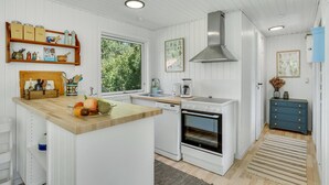 Una cocina moderna con armarios blancos, una isla de madera, horno empotrado y campana extractora de acero inoxidable.
