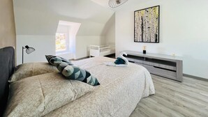 Une chambre à coucher avec un grand lit, une table de chevet, une lampe fixée au mur, une fenêtre et un tableau.