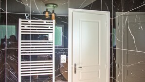Une pièce avec une porte blanche, une fenêtre avec des stores et un mur en marbre.
