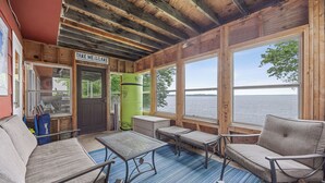 Una cabaña con interior de madera y vistas al lago, con un letrero que dice 'TAKE ME TO THE LAKE'.