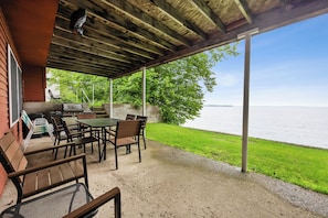 Eine Terrasse im Freien mit Grill, Sitzgelegenheit und Blick aufs Wasser.