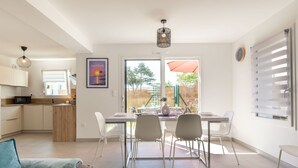 A modern kitchen with white cabinets, a microwave, and a dining area with a table and chairs. - Beautiful  villa for 6 people with WIFI, TV, terrace and pets allowed (Royan)