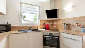 A modern kitchen with a microwave, stove, oven, and a window with blinds. - Beautiful  villa for 6 people with WIFI, TV, terrace and pets allowed (Royan)