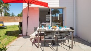 An outdoor patio with a table and chairs, a red umbrella, and a sliding glass door leading to an interior space. - Beautiful  villa for 6 people with WIFI, TV, terrace and pets allowed (Royan)