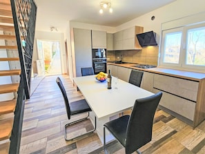 Una cocina moderna con comedor, suelo de madera y televisor sobre la encimera.