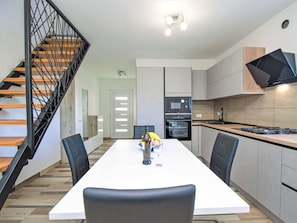 Una cocina moderna con comedor, escalera de madera y electrodomésticos integrados.