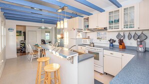 Una cocina moderna con una isla central, muebles blancos y detalles azules.