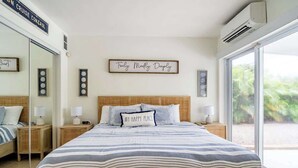 A bedroom with a large bed, a bedside table, a nightstand, a mirror, and a window with a view of greenery. - Backyard Oasis, Htd Pool/Hot Tub, Beaches, No Fees (Sarasota)