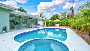 A swimming pool with a curved edge, surrounded by a covered patio area with chairs and a table. - Backyard Oasis, Htd Pool/Hot Tub, Beaches, No Fees (Sarasota)