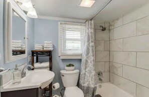 A bathroom with a sink, toilet, and shower area.