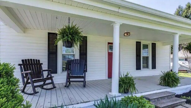 A porch with two rocking chairs and a hanging plant.