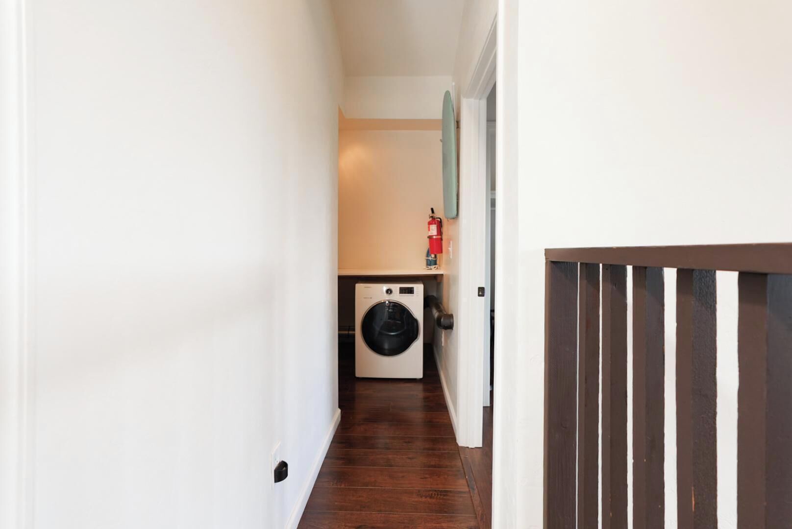Une buanderie équipée d’un lave-linge, d’un extincteur et d’une porte en bois.