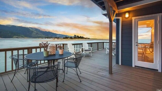 A wooden deck with a table and chairs, overlooking a body of water and distant mountains. - Bolinas Beach Home - Over the water with spectacular views (Bolinas)