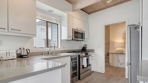 A modern kitchen with white cabinetry, a stainless steel range, a microwave, and a refrigerator. - Bolinas Beach Home - Over the water with spectacular views (Bolinas)