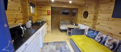 L'intérieur d'une cabane en bois comprend un coin cuisine, un canapé et un lit.