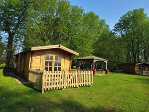 Une cabane en bois avec une cour clôturée, une table de pique-nique et un kiosque.