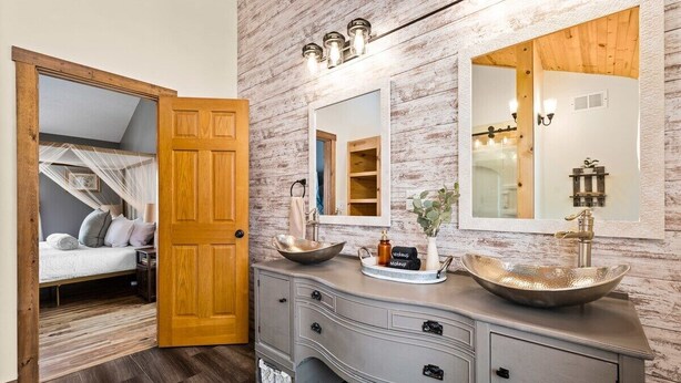 A bathroom with a wooden door, a vanity with a large bowl sink, and a mirror above the sink. - Farmhouse Retreat*Great View*Hot Tub*Wineries (Traverse City)