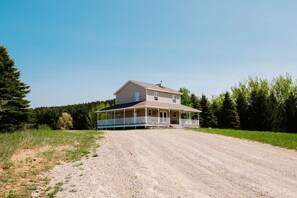 Ein zweistöckiges Haus mit Veranda und einem Schotterweg.