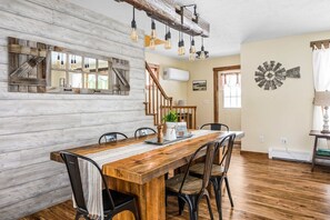 A dining area with a wooden table and chairs, a rustic wall, and a windmill decoration. - Farmhouse Retreat*Great View*Hot Tub*Wineries (Traverse City)