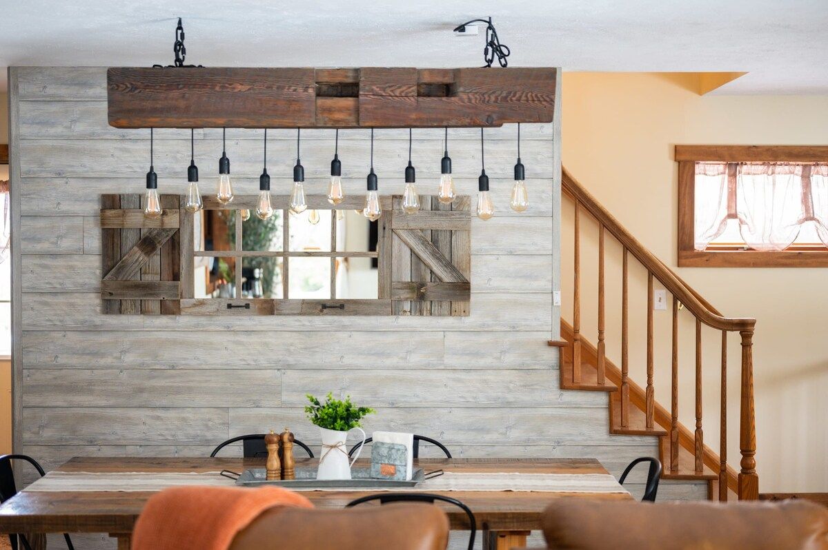 A dining area with a wooden table, chairs, and a hanging light fixture above.