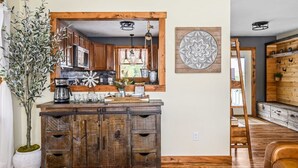 A rustic kitchen with wooden cabinets, a coffee station, and a decorative wall piece. - Farmhouse Retreat*Great View*Hot Tub*Wineries (Traverse City)
