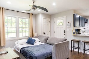 Una camera da letto moderna con un letto, una ventola a soffitto e vista all'aperto attraverso ampie finestre.