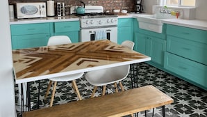 Une cuisine avec des armoires de couleur turquoise, une table en bois et un sol à motifs.