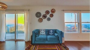 Un salon avec un canapé bleu, un tapis coloré et des assiettes décoratives accrochées au mur.