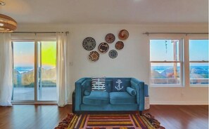 Ein Wohnzimmer mit einem blauen Sofa, einem bunten Teppich und dekorativen Tellern an der Wand.