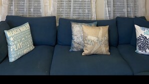 A living room with a dark blue sofa, white sheer curtains, and a ceiling fan. - Cozy, Clean, Convenient With A Beach Feel (Cape Coral)