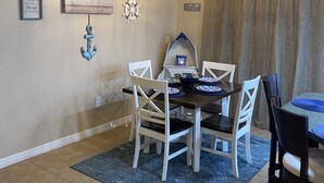 A dining area with a wooden table and chairs, a chandelier, and nautical-themed wall decor. - Cozy, Clean, Convenient With A Beach Feel (Cape Coral)