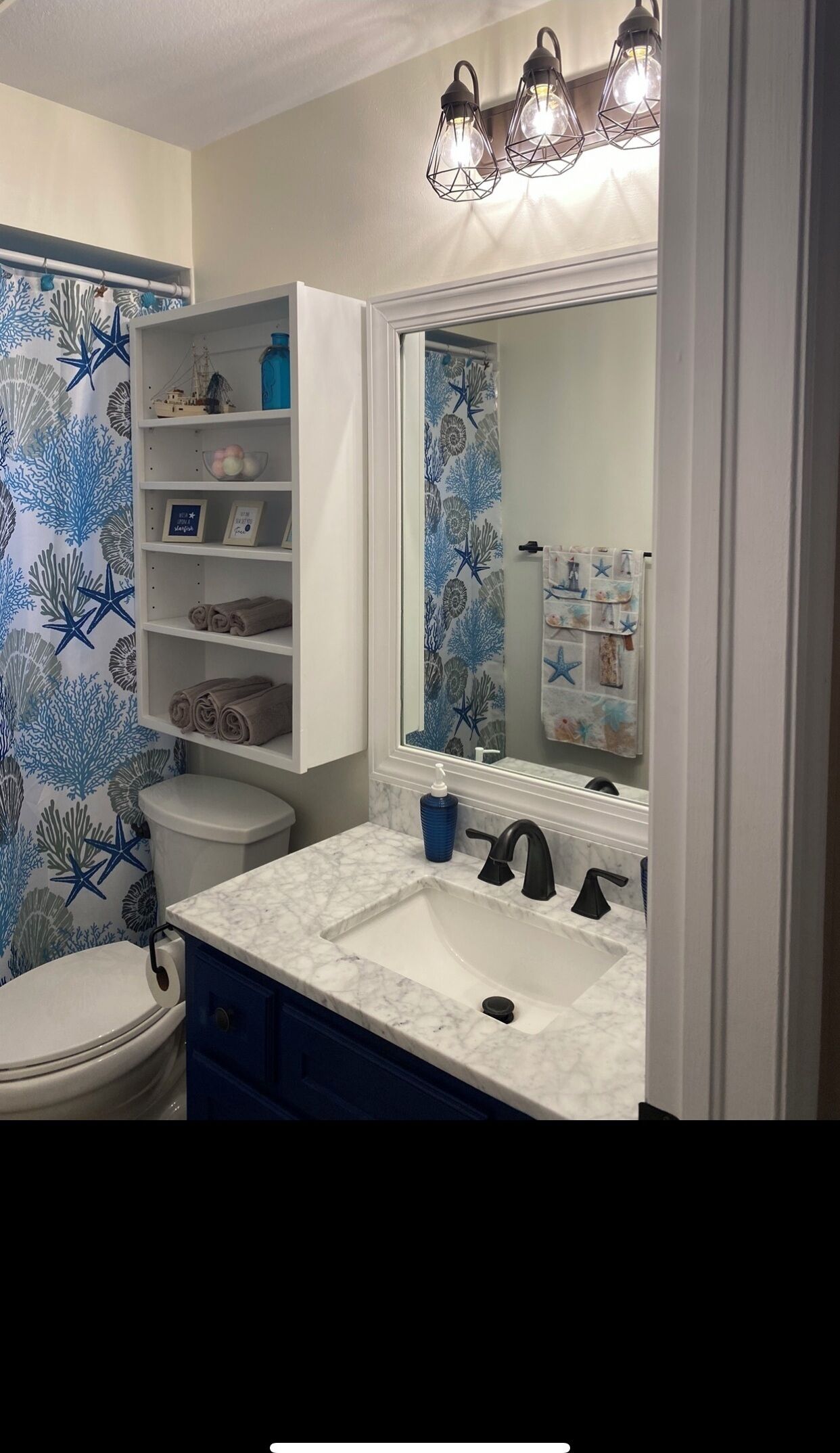 A bathroom with a toilet, a sink with a mirror, and shelves above the sink.
