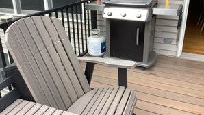 A wooden deck with a grill and a chair. - The Farmhouse- country charm, room for family visiting, relaxing, or gathering  (West Union)