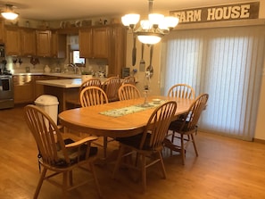 A dining area with a wooden table and chairs, a chandelier, and a 'Farm House' sign.