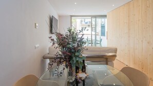 Un espace repas moderne avec une table en verre, deux chaises, un banc et un mur en bois.