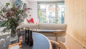 A modern living room with a round table, a sofa, and a view of the city through large windows. - My Space Barcelona apartment with large terrace close to Barraquer clinic (Barcelona)
