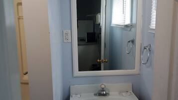 A bathroom with a white sink, a mirror above it, and a door with a brass handle.