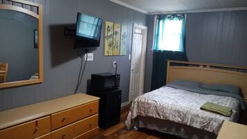 A bedroom with a bed, dresser, television, and artwork on the wall.