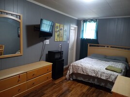 A bedroom with a bed, dresser, television, and artwork on the wall.